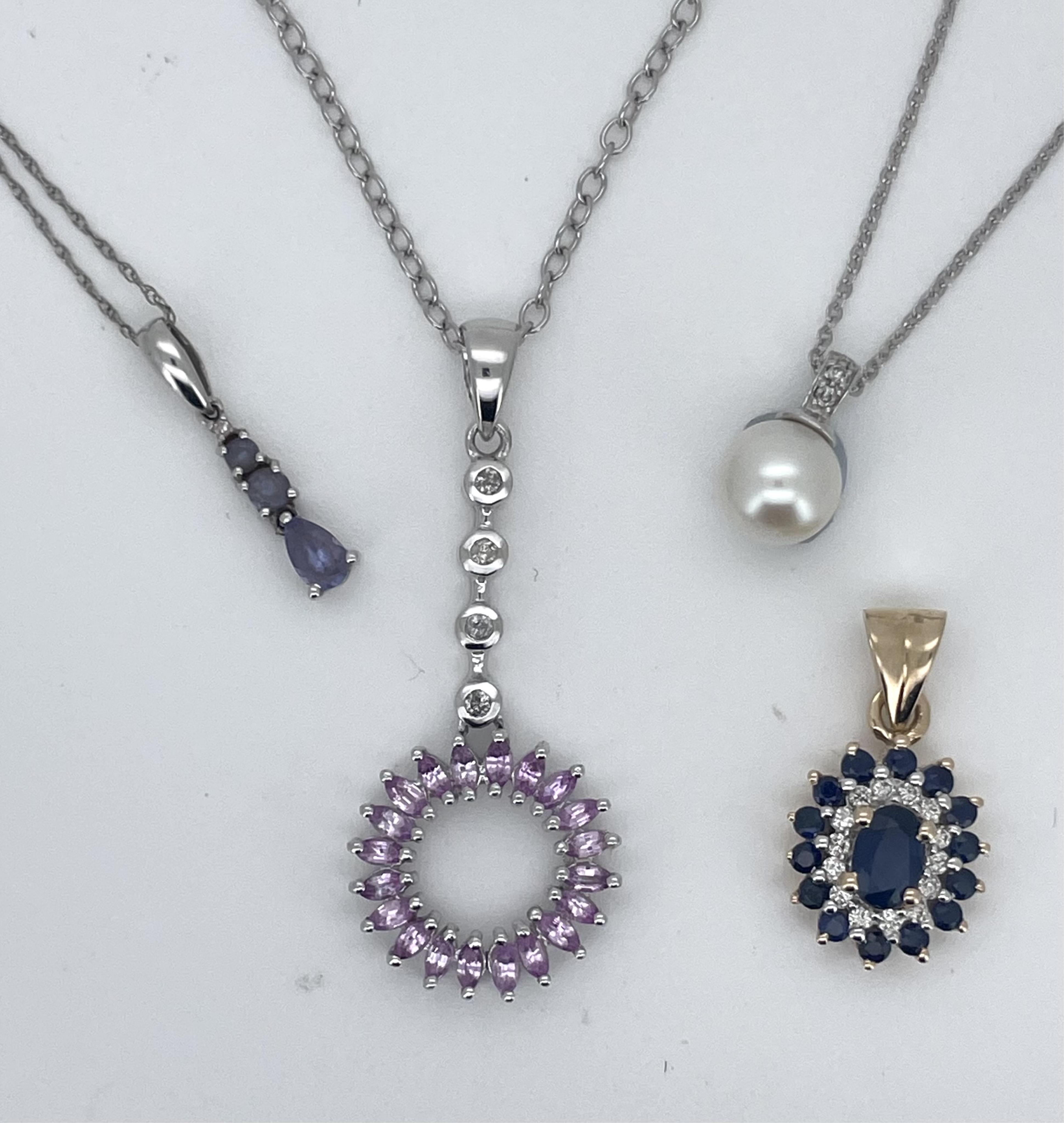 A modern 9ct gold, sapphire and diamond set oval cluster pendant, overall 20mm, together with three assorted 9ct white gold or 375 and gem set pendants including cultured pearl, with 375 white metal chains, gross weight